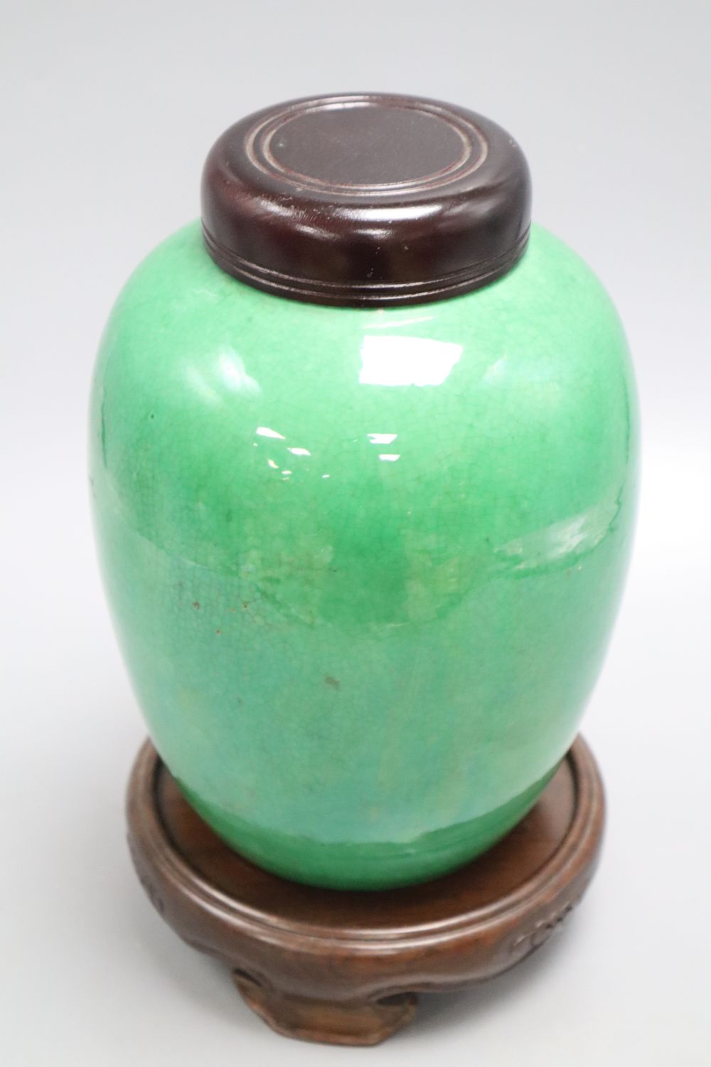 A 19th century Chinese green crackle glaze jar, drilled, wood cover and stand, overall height 25cm